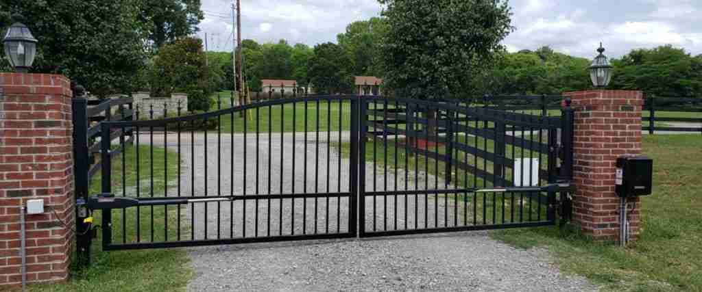 EVERLAST GATES & FENCE automated dual-swing driveway gate between brick columns.