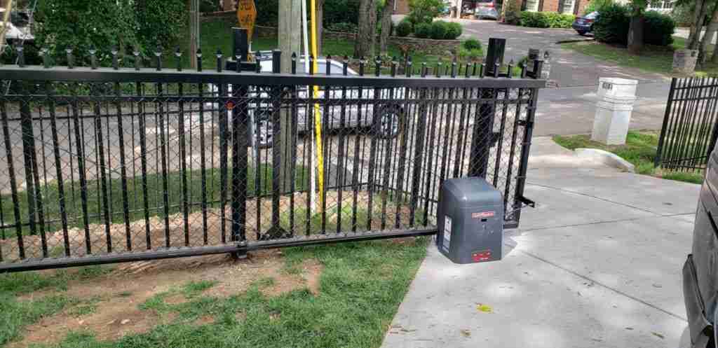 Automatic sliding black metal gate with LiftMaster operator by driveway.