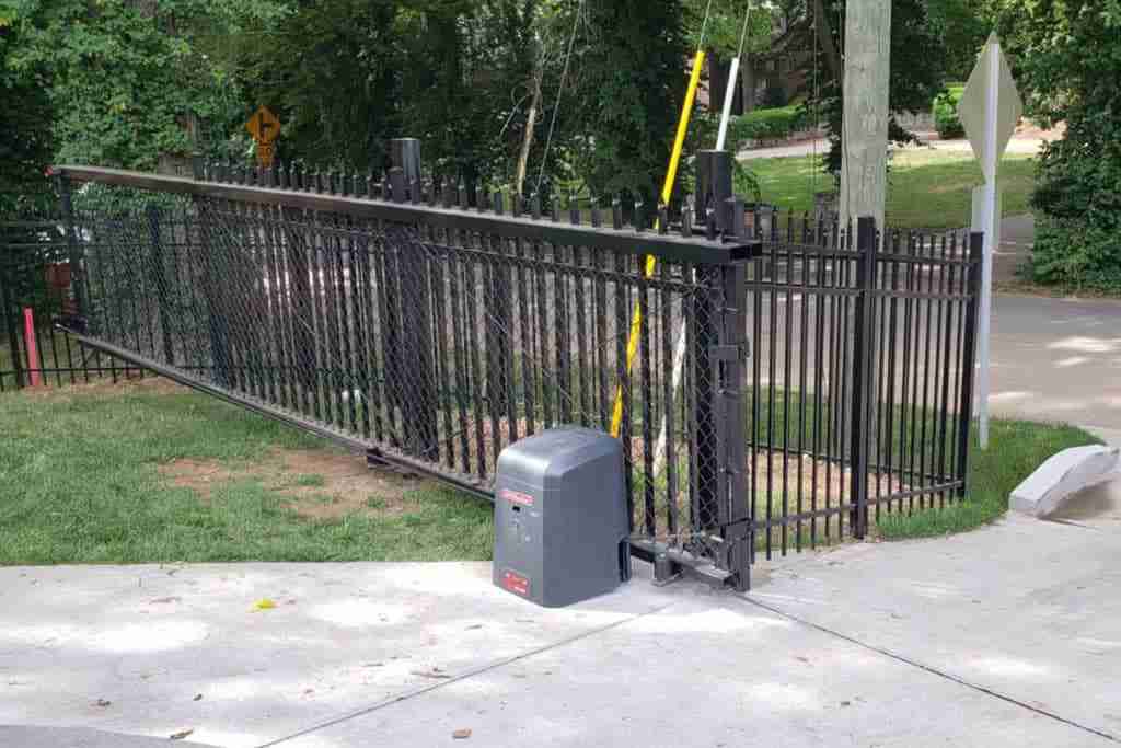Sliding chain-link gate with motor operator on concrete pad.
