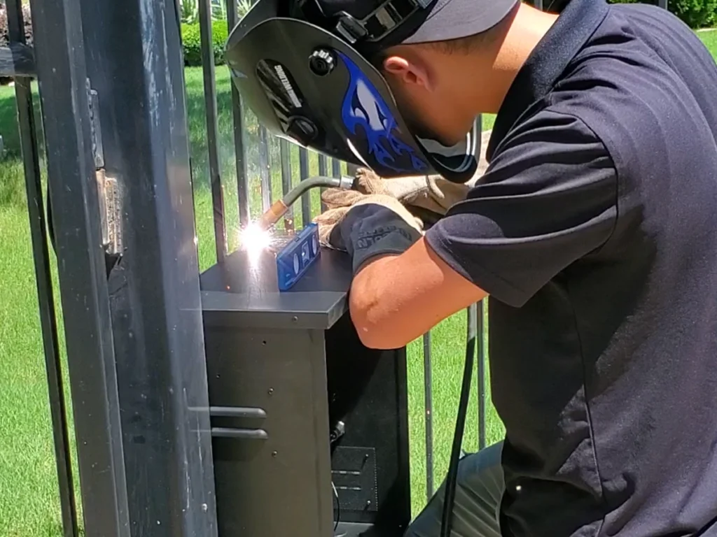Technician lubricating an electric gate system in San Antonio