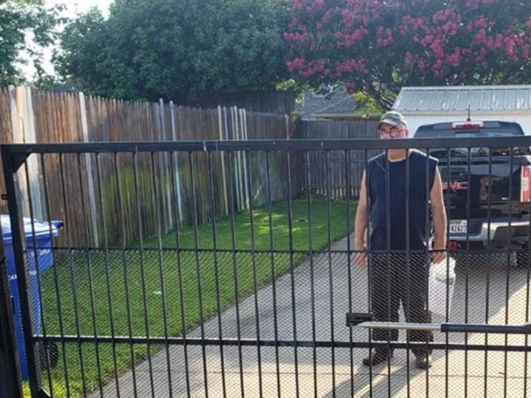 Technician inspecting a metal sliding gate for rust and alignment in Farmers Branch, TX
