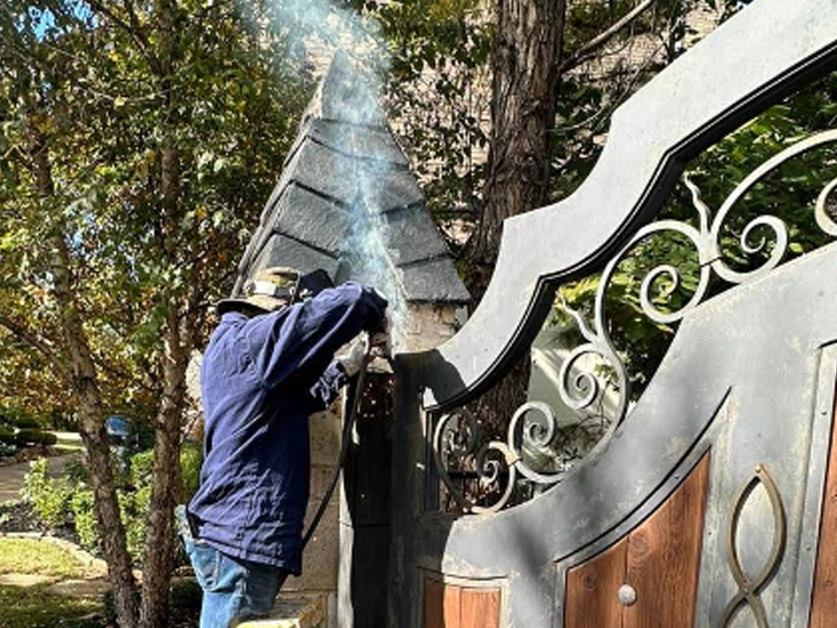 Technician fixing a stuck residential gate in Carrollton TX for Everlast Gates & Fence