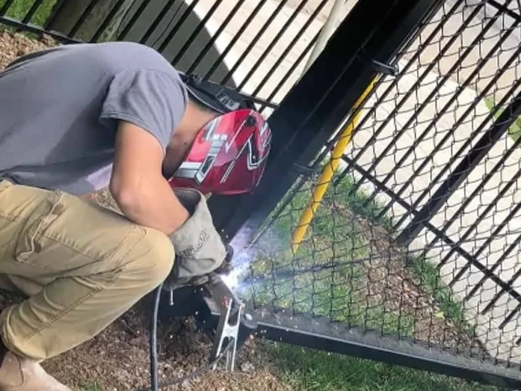 Technician repairing a rusted and misaligned iron gate in Dallas, Texas