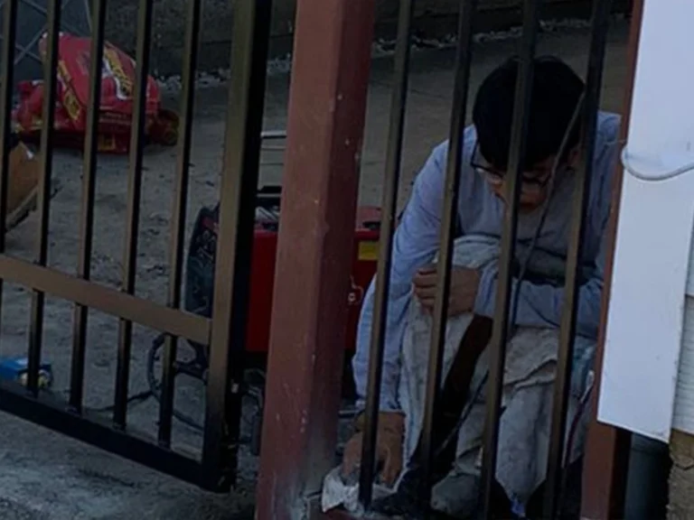 Technician repairing an iron gate in Farmers Branch, TX with Everlast Gates & Fence tools.