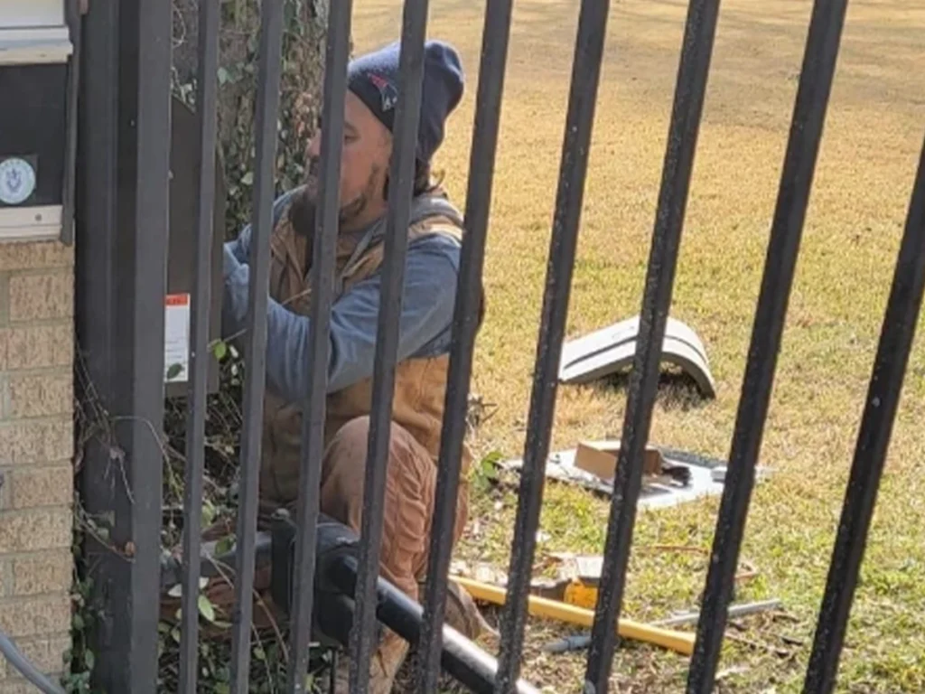 A professional technician repairing a residential gate in a Garland, TX neighborhood