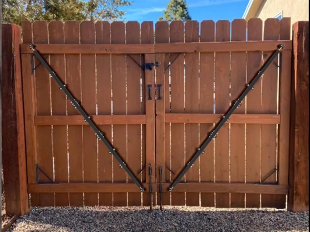 Repaired wood fence gates strengthened with a diagonal brace, new hinges, and a stable post in Farmers Branch