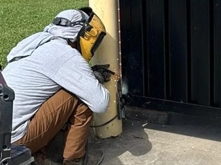 Homeowner performing seasonal fence and gate maintenance during autumn.