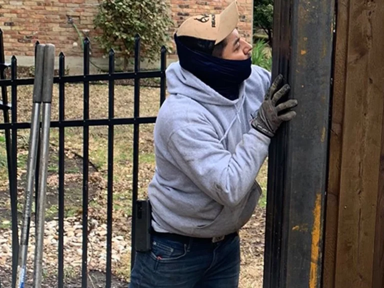 Technician repairing a sliding driveway gate in Dallas, TX with Everlast Gates & Fence